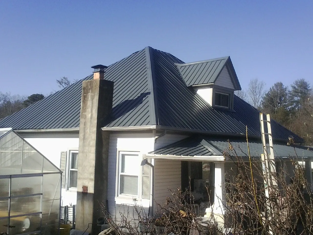 Dark blue standing seam metal roof on a white farmhouse with dormer — Slate & Tile Roof Repair by Roofing Brothers in Haddon Heights