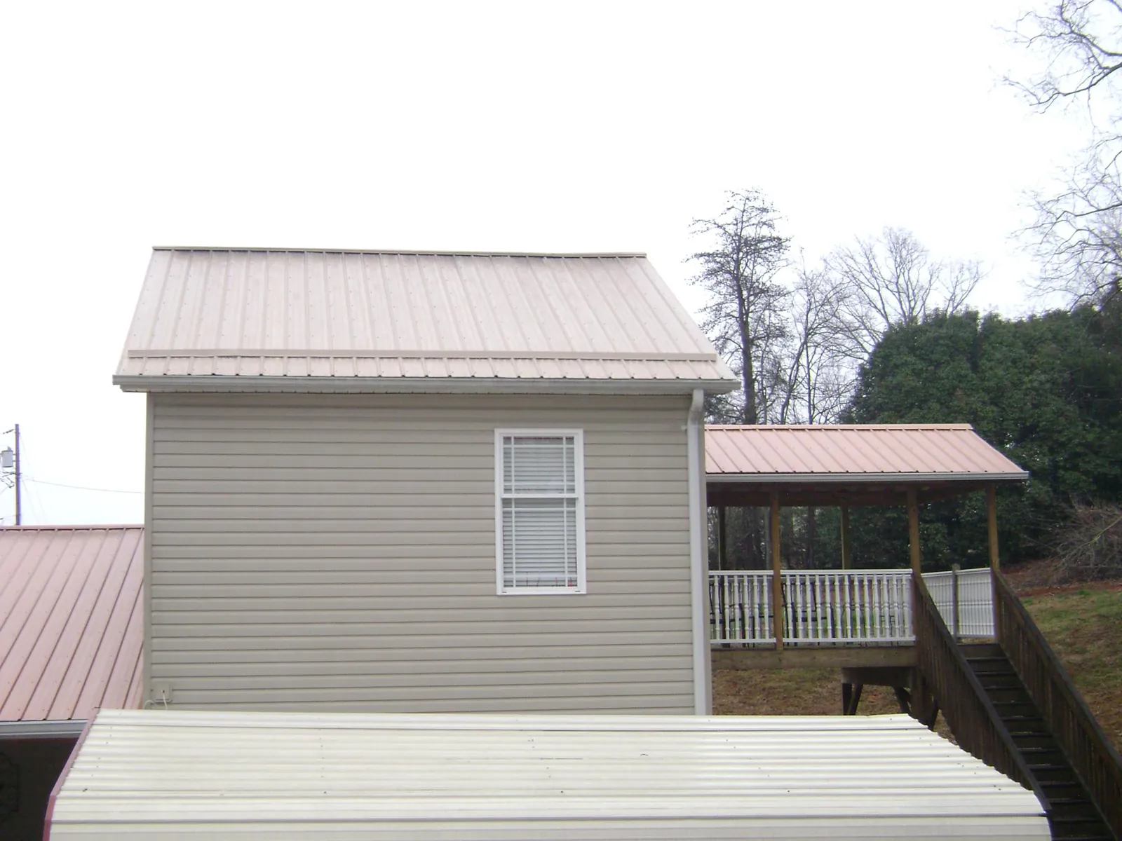 Tan metal roofs on a two story addition and attached porch, from a Roof Replacement job in Haddon Heights