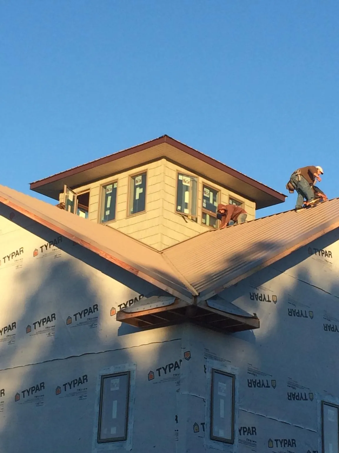Roofers working around a rooftop cupola on a new metal roof at sunset — Roof Waterproofing in Haddon Heights by Roofing Brothers